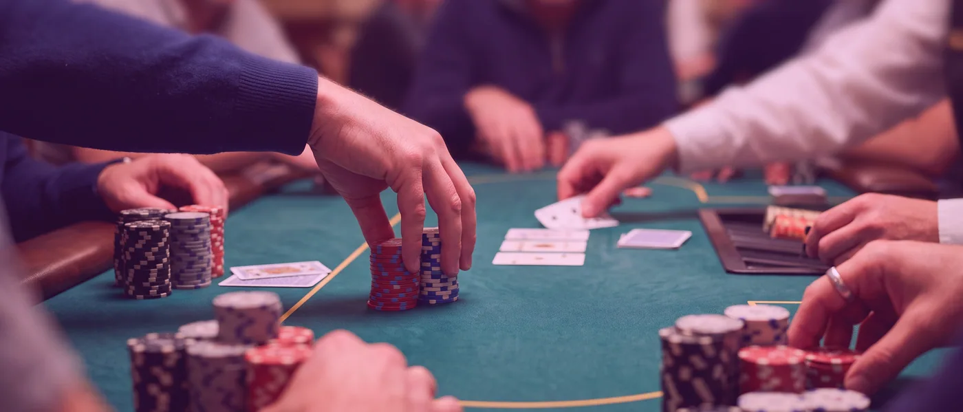 A gloved hand arranging a short stack of chips at the edge of a card table